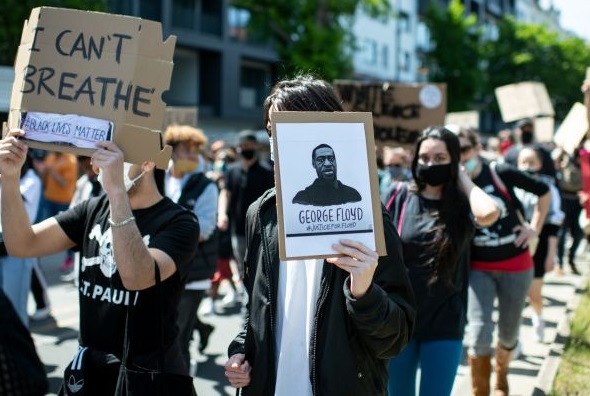 Protesters in Berlin with signs stating I can't breathe and black lives matter 