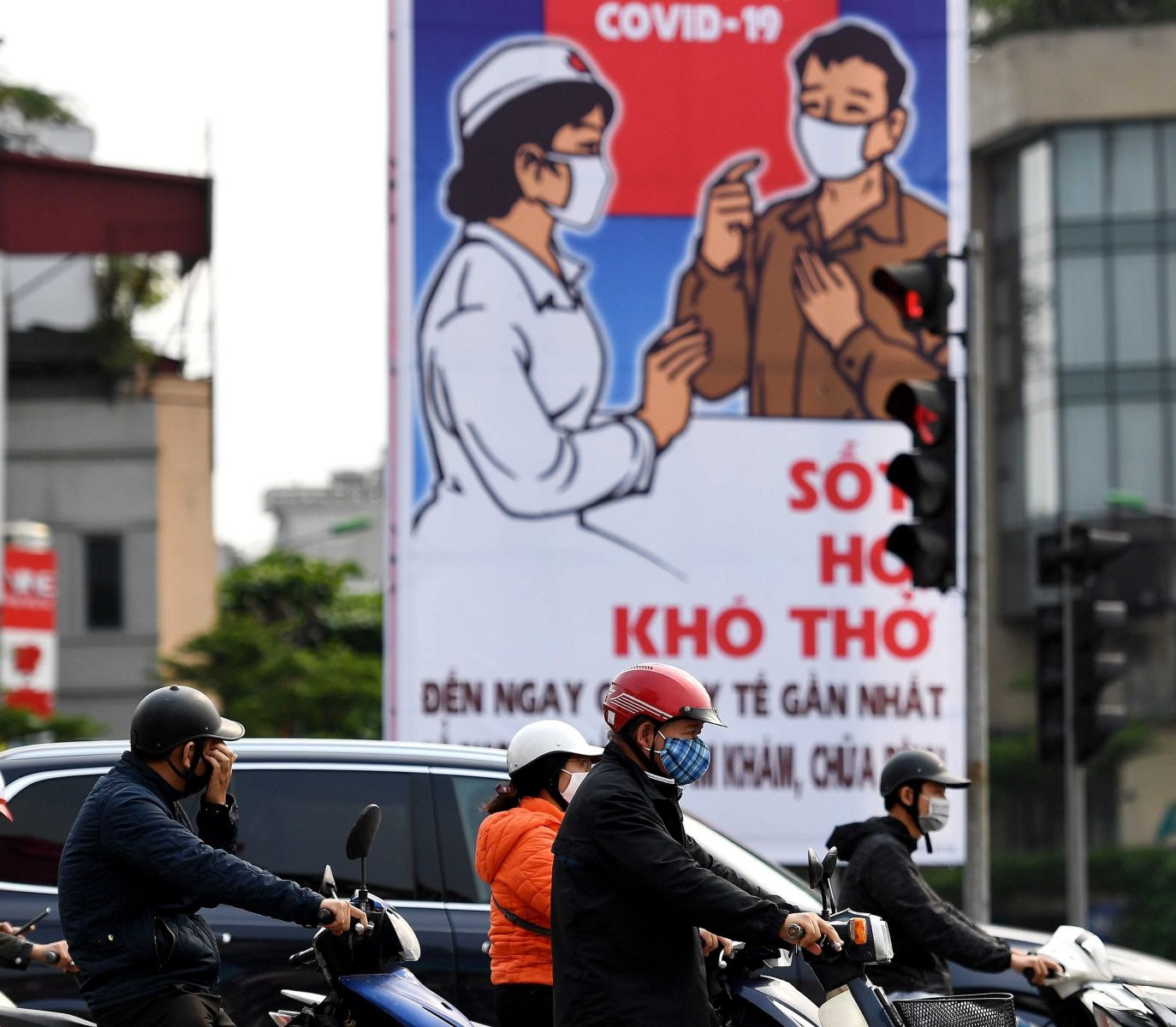 motorcycles on busy Hanoi street passing by billboard uging masks to prevent against Covid-19